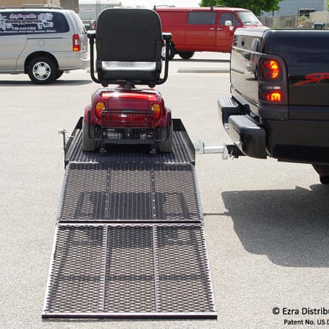 Versahaul mobility scooter carrier installed on back of truck with extended ramp loaded with scooter side view