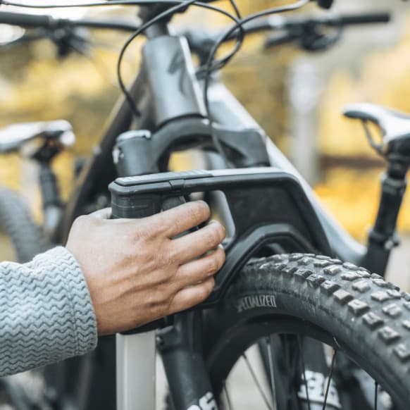 Close-up of latching system on Thule Verse bike rack. Persons hand is pulled up the latching arm on tire.
